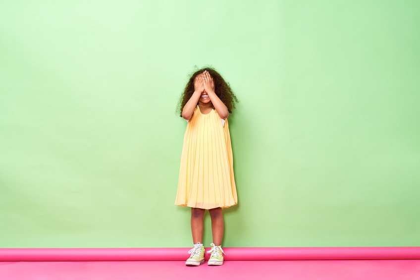 young girl closing her eyes with hand with happy expression