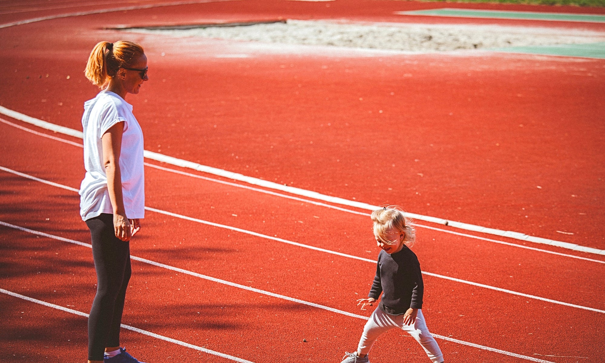 yong mother and little daughter standing in running court