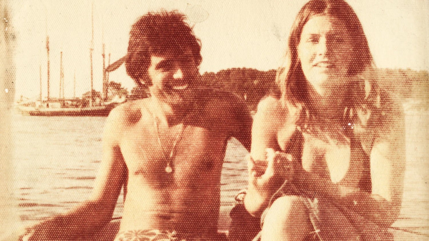 photo of young man and woman in the 70s with a boat in the background