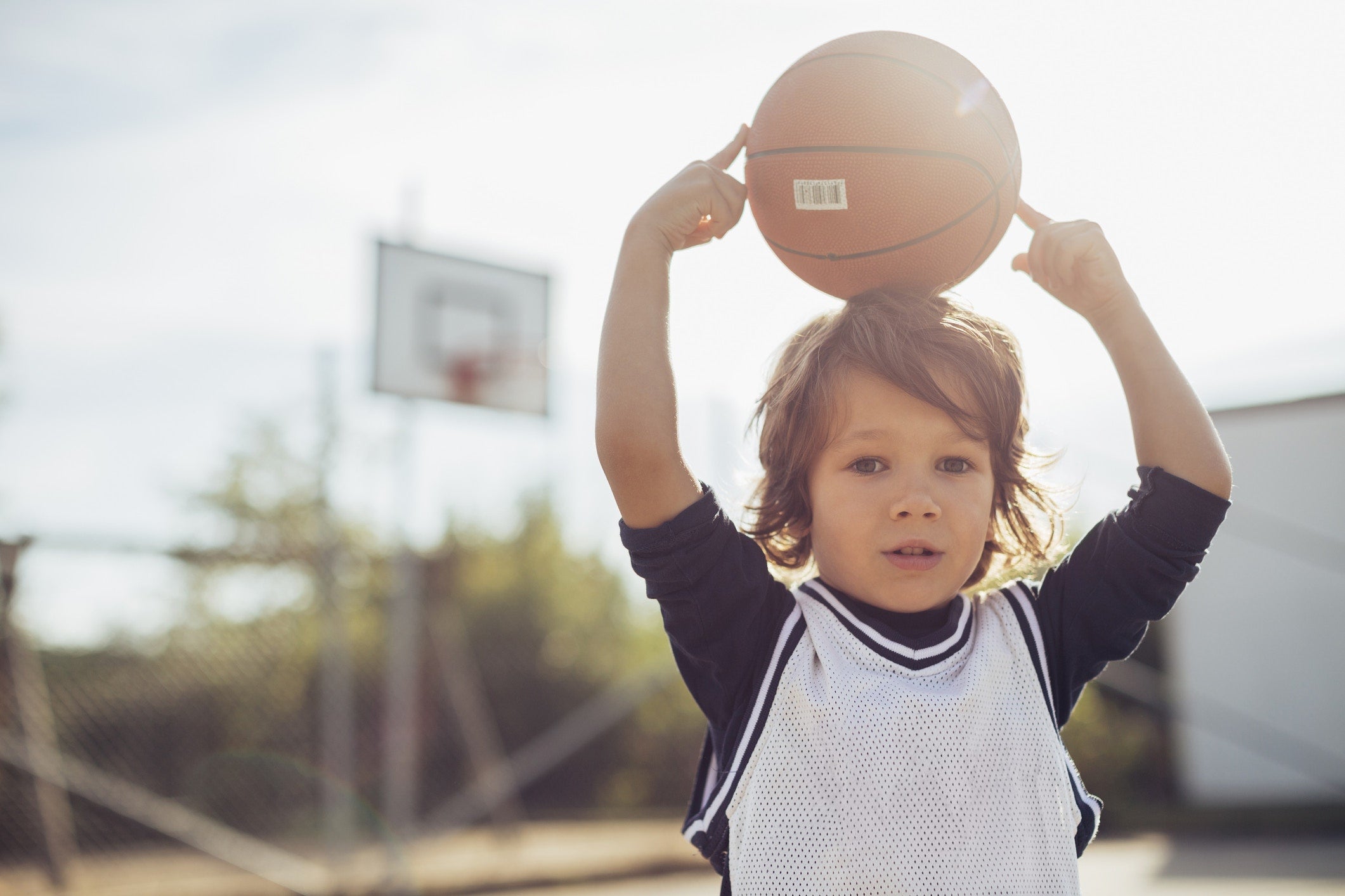 Child holding the basket ball on his head 