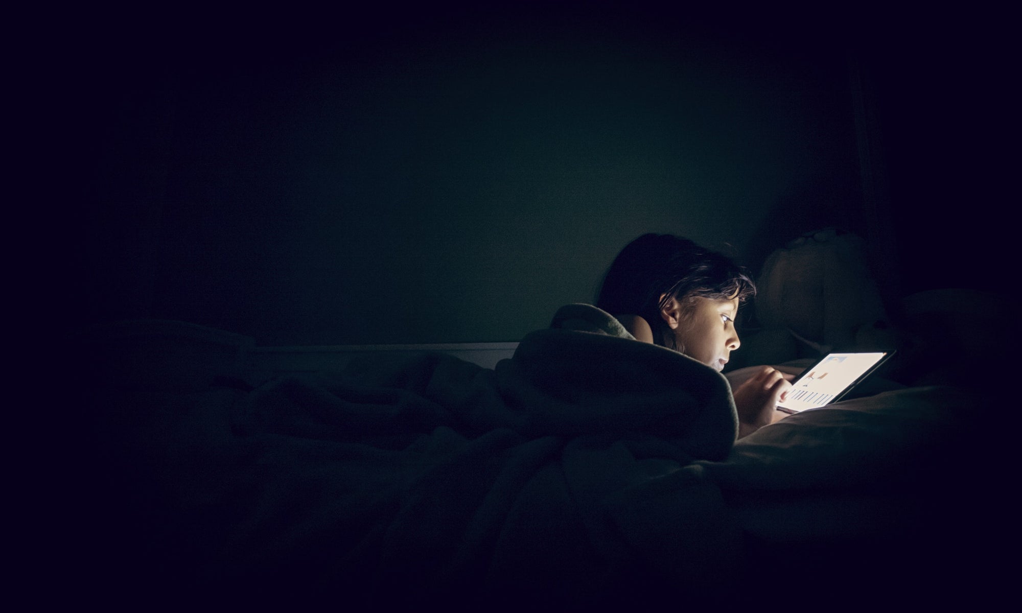 A person using tab in bed in a dark room