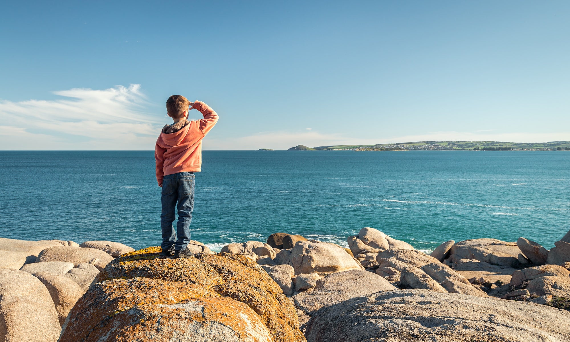 A child standing on the sea shore and watching waves 