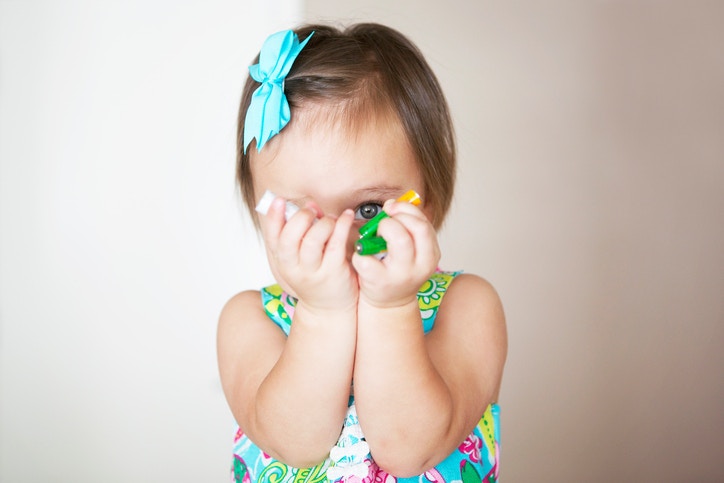 young little girl holding batteries and covering her face