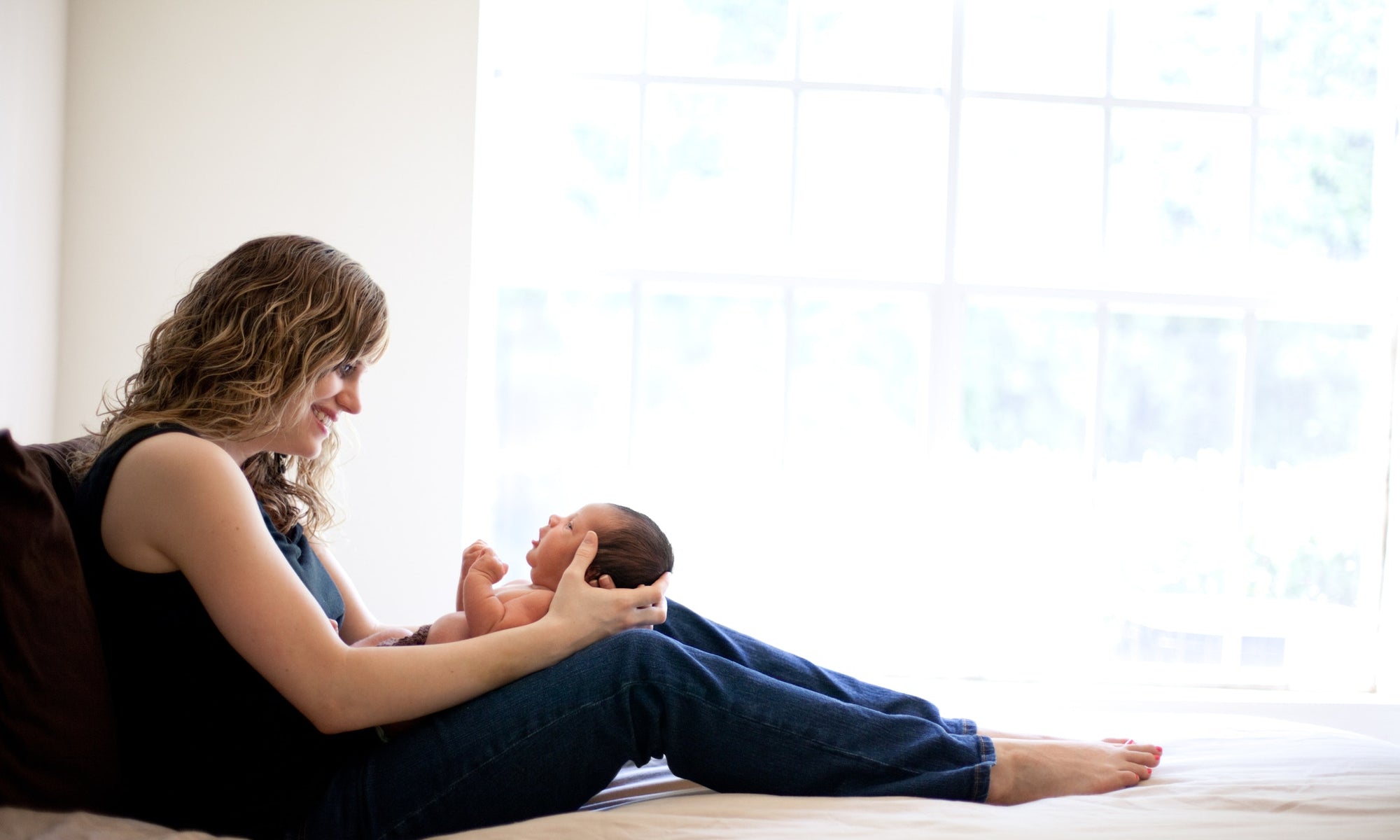 Young mother holding her newborn son in bed