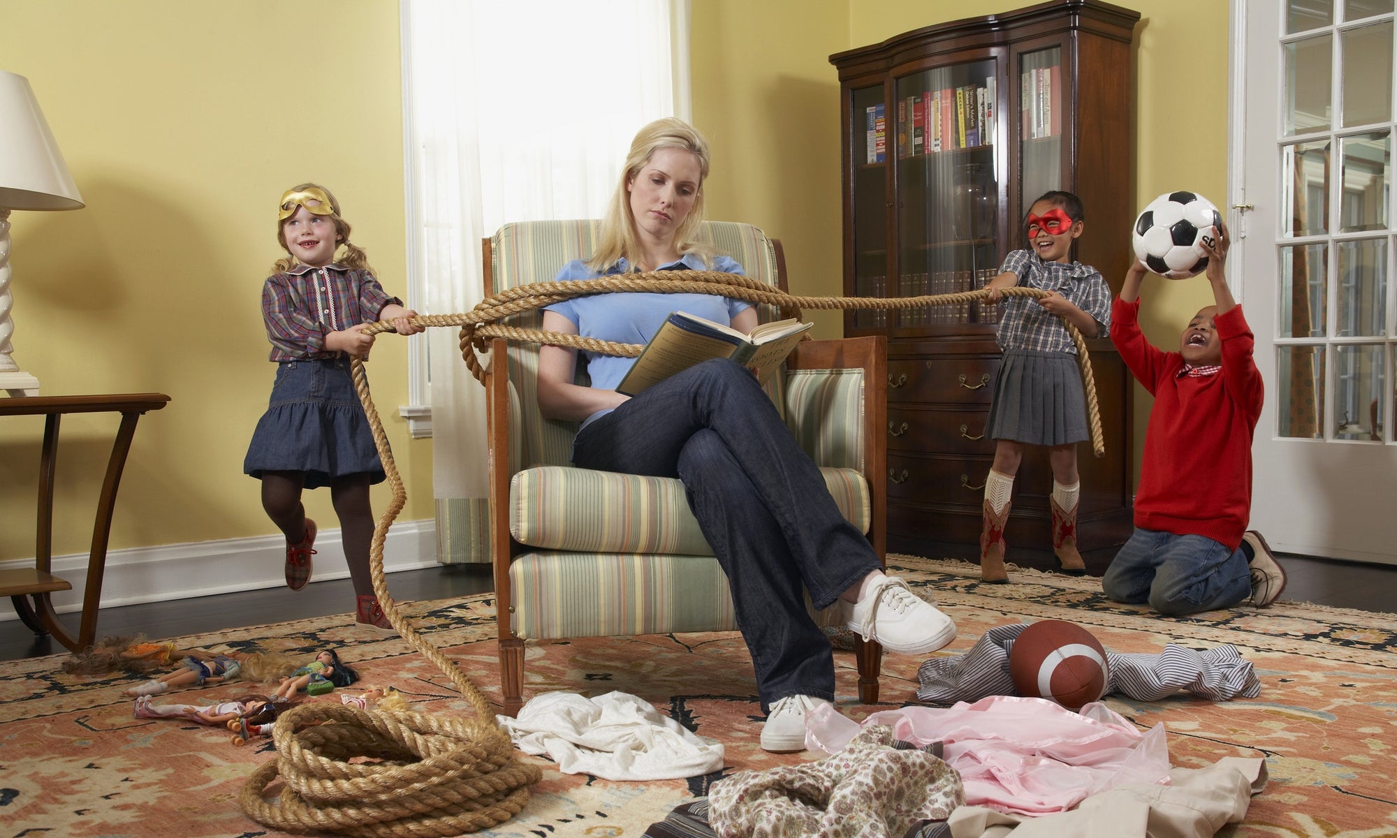 Three children tying mother with rope in living room