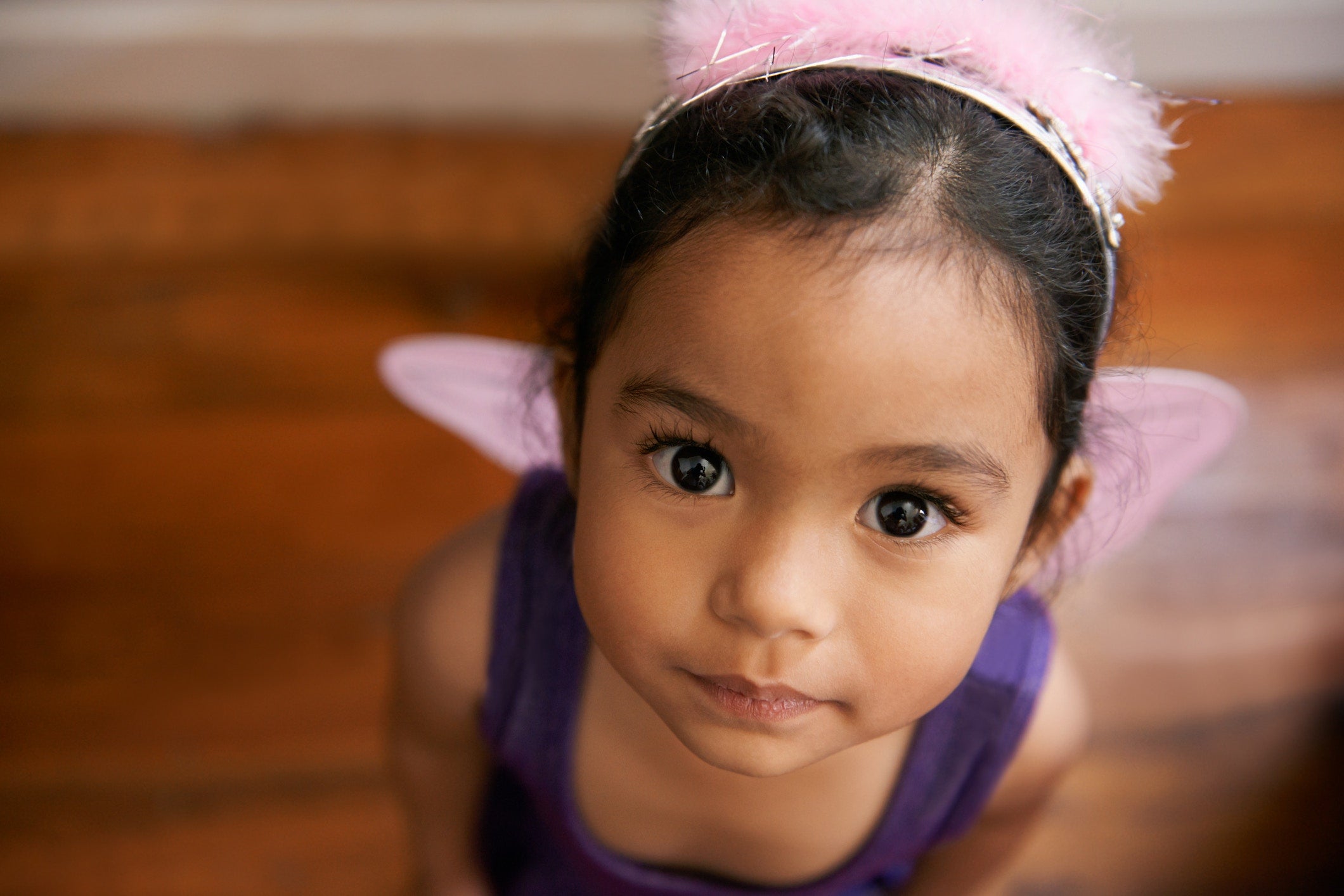 little girl wearing pink hair band and looking up