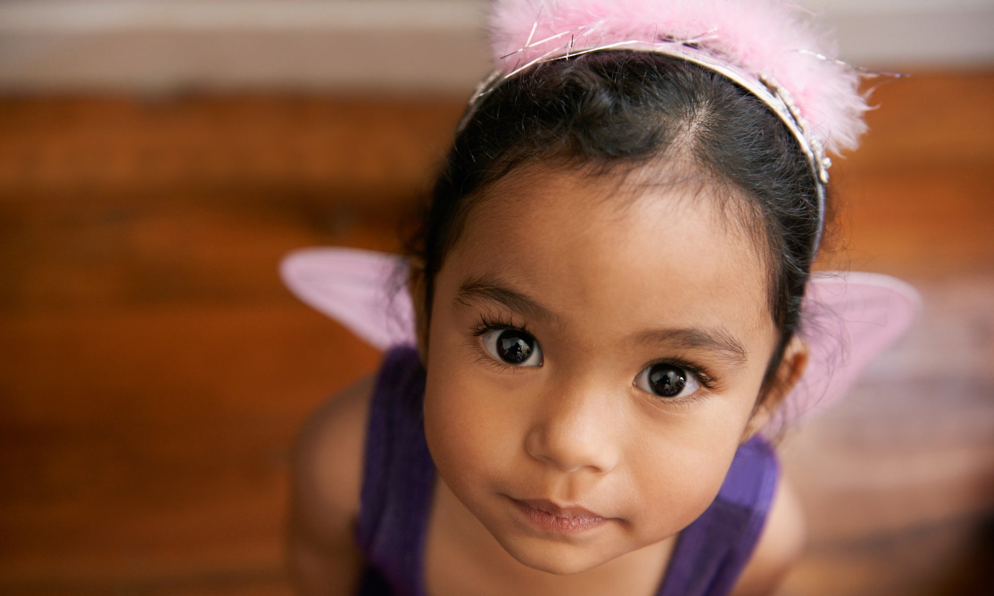 little girl wearing pink hair band and looking up