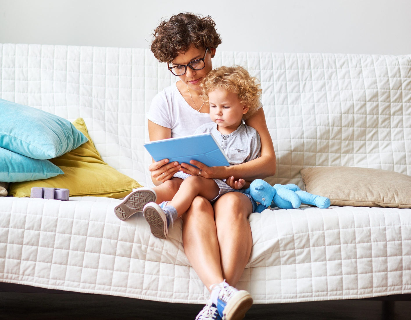 son sitting on mother lap watching cartoons on tablet