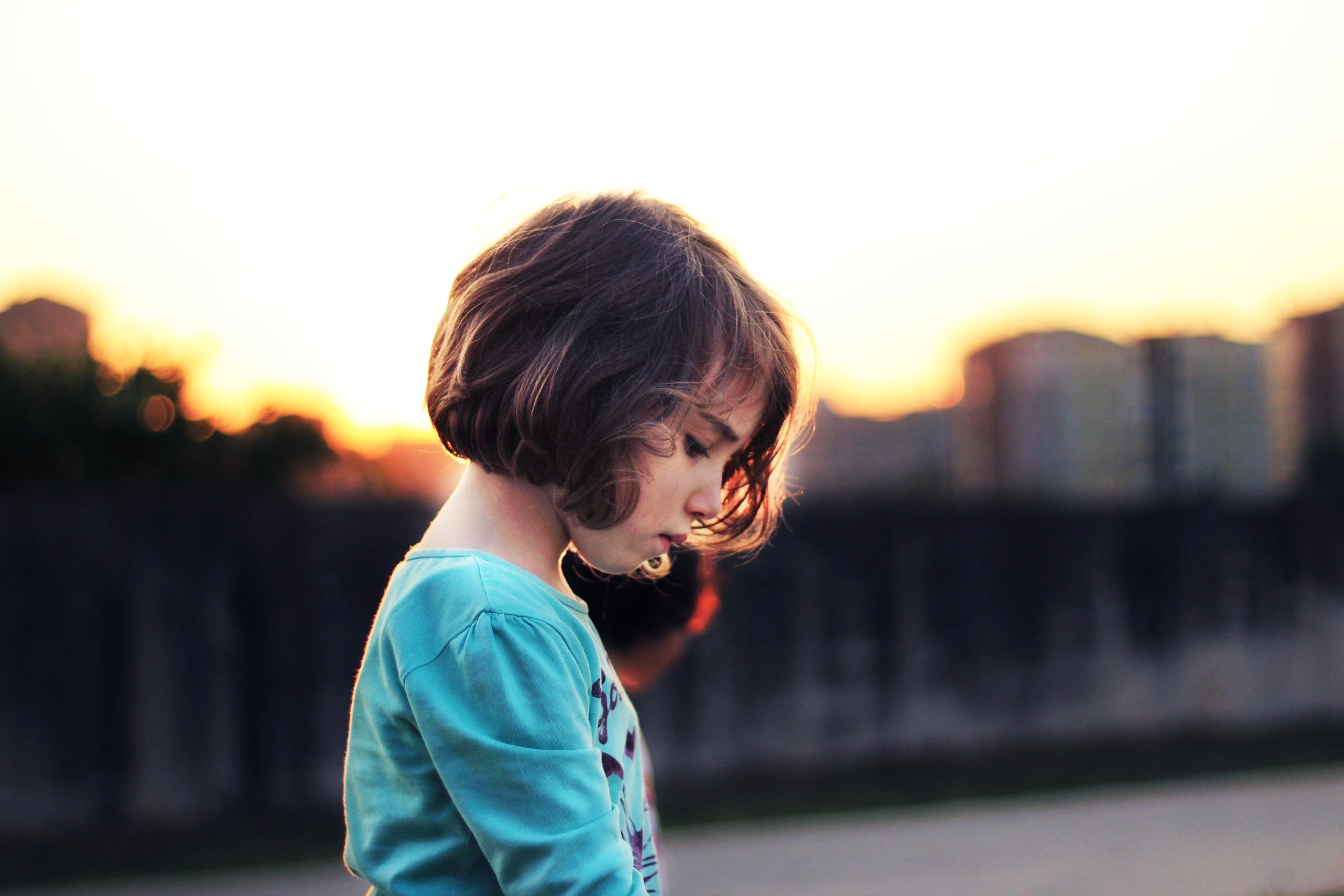 sad little girl standing on the road at asunset time