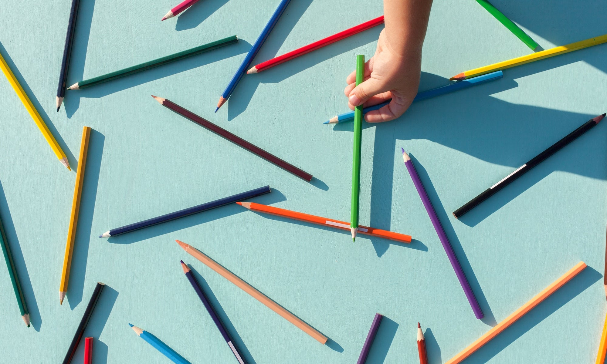  colored pencils scattered on blue background