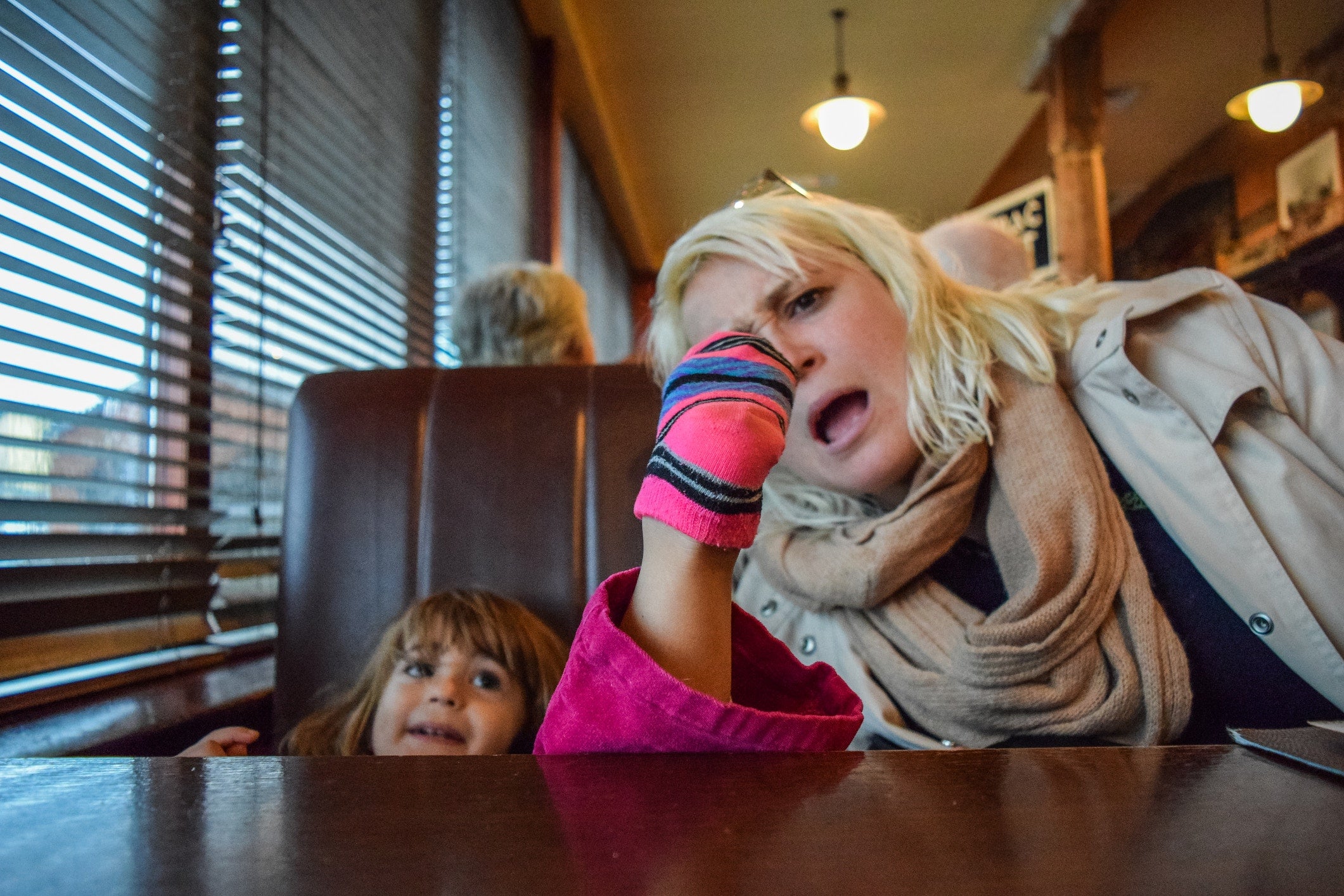 mother looking at  her little girl's sock and sitting on the cafe