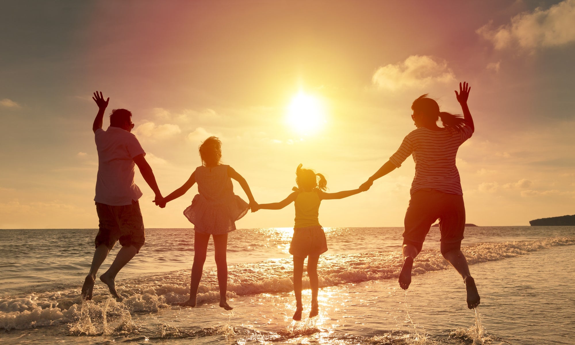 family enjoying and jumping in the air on a beach