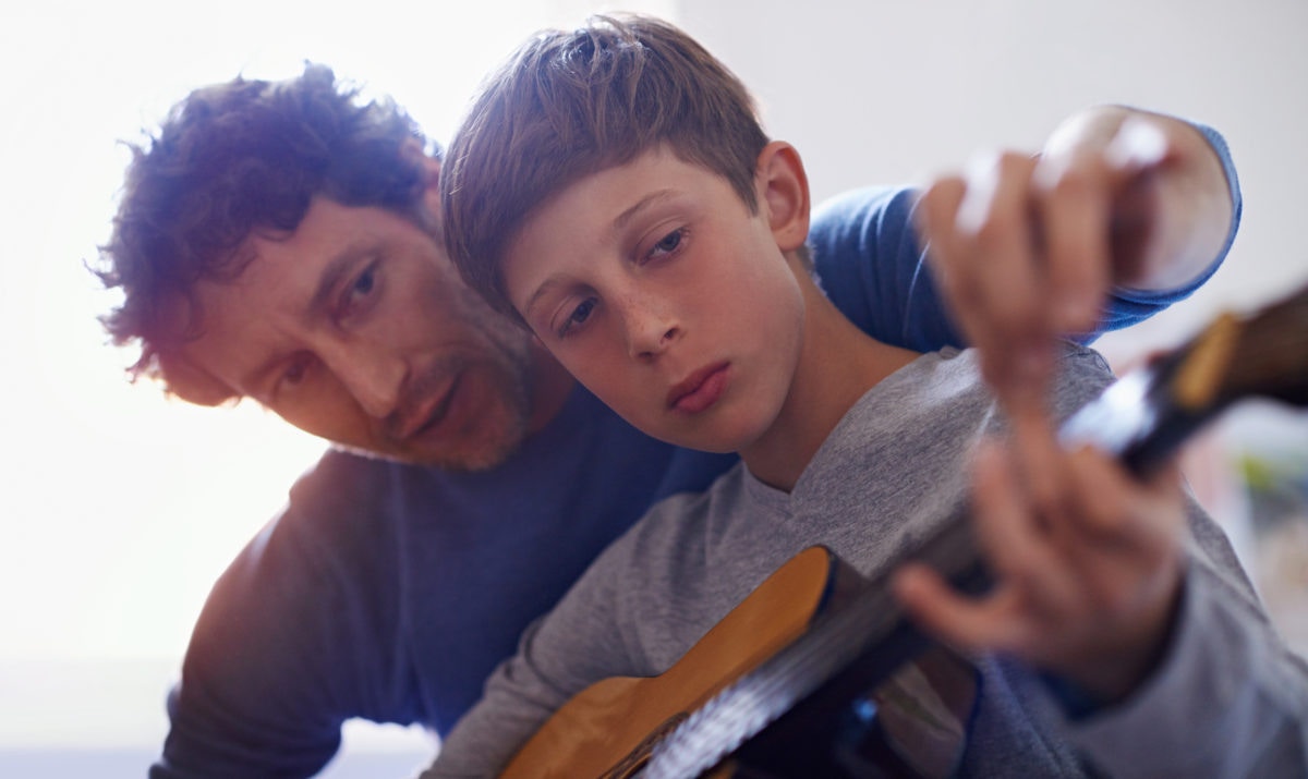 A Teacher Teaching guitar to student