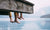 father and son sitting, dangling feet over tranquil lake dock