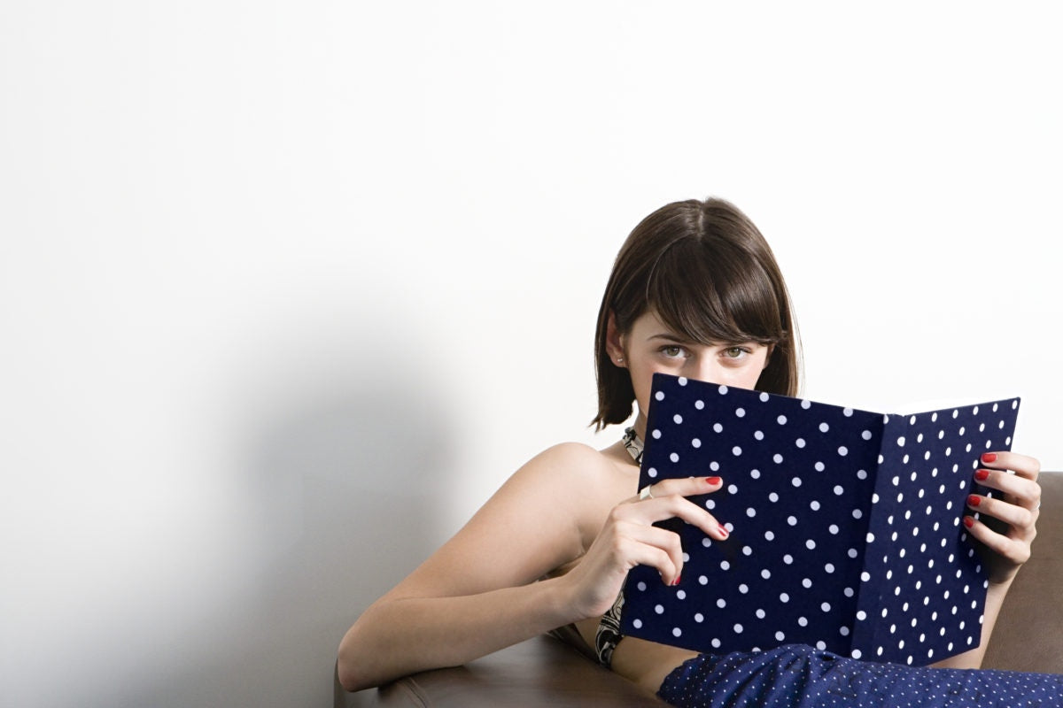 young girl peeking over her book