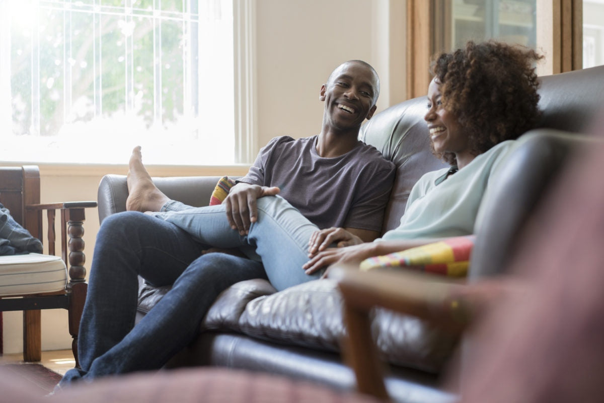 Two guys are felling happy , laughing each other by sitting on  a sofa