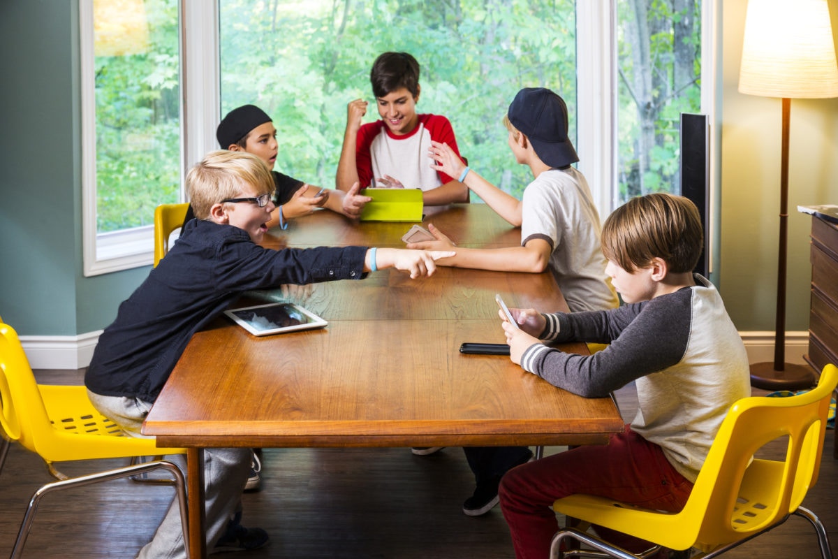 Group of boys are discussing and playing using mobile