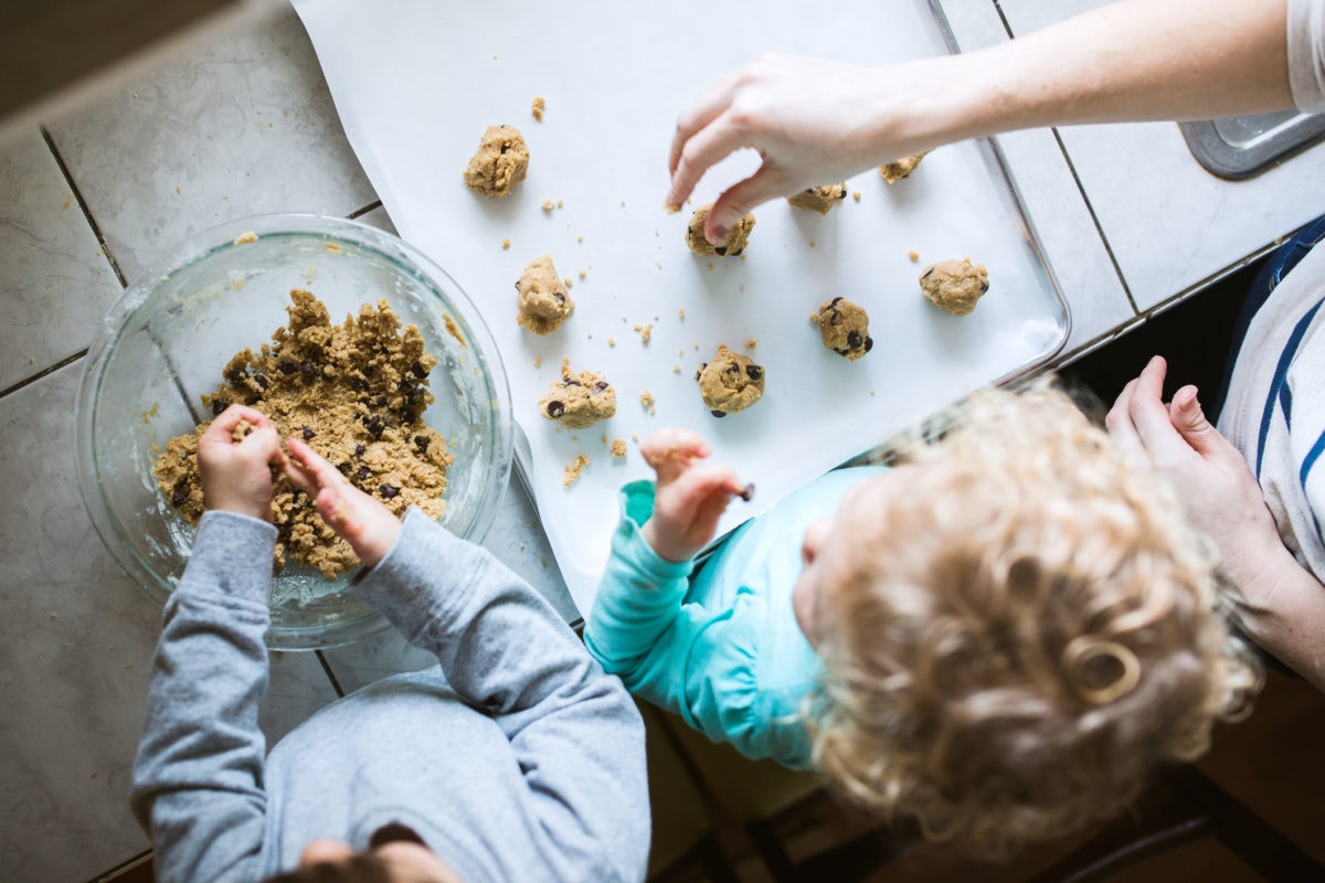 father and sons baking cookies in kitchen