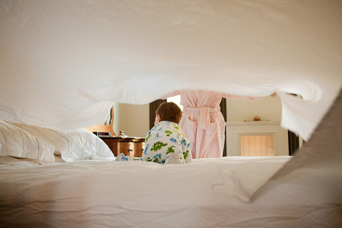 mother and baby son making bed 