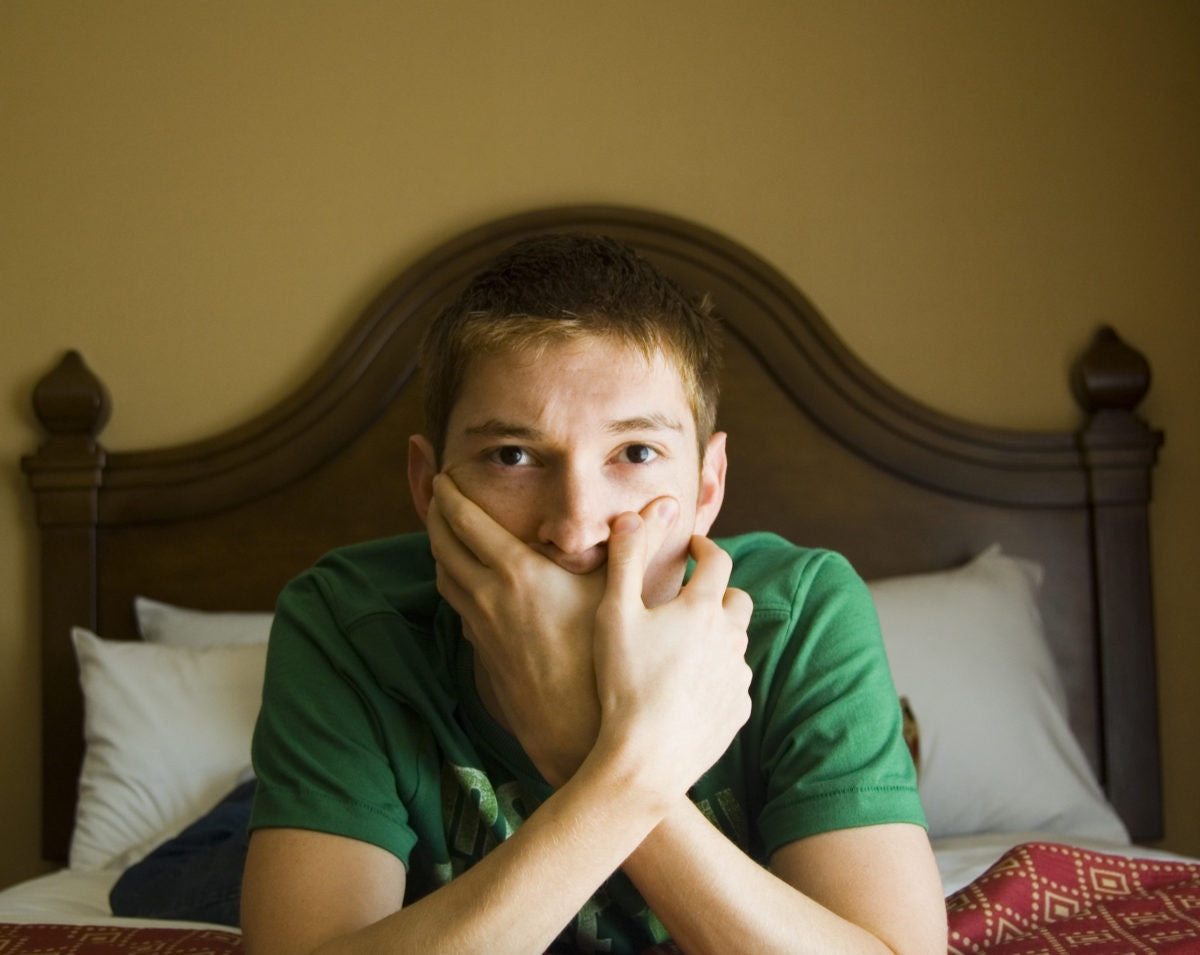 young man lying on his belly and closing his mouth