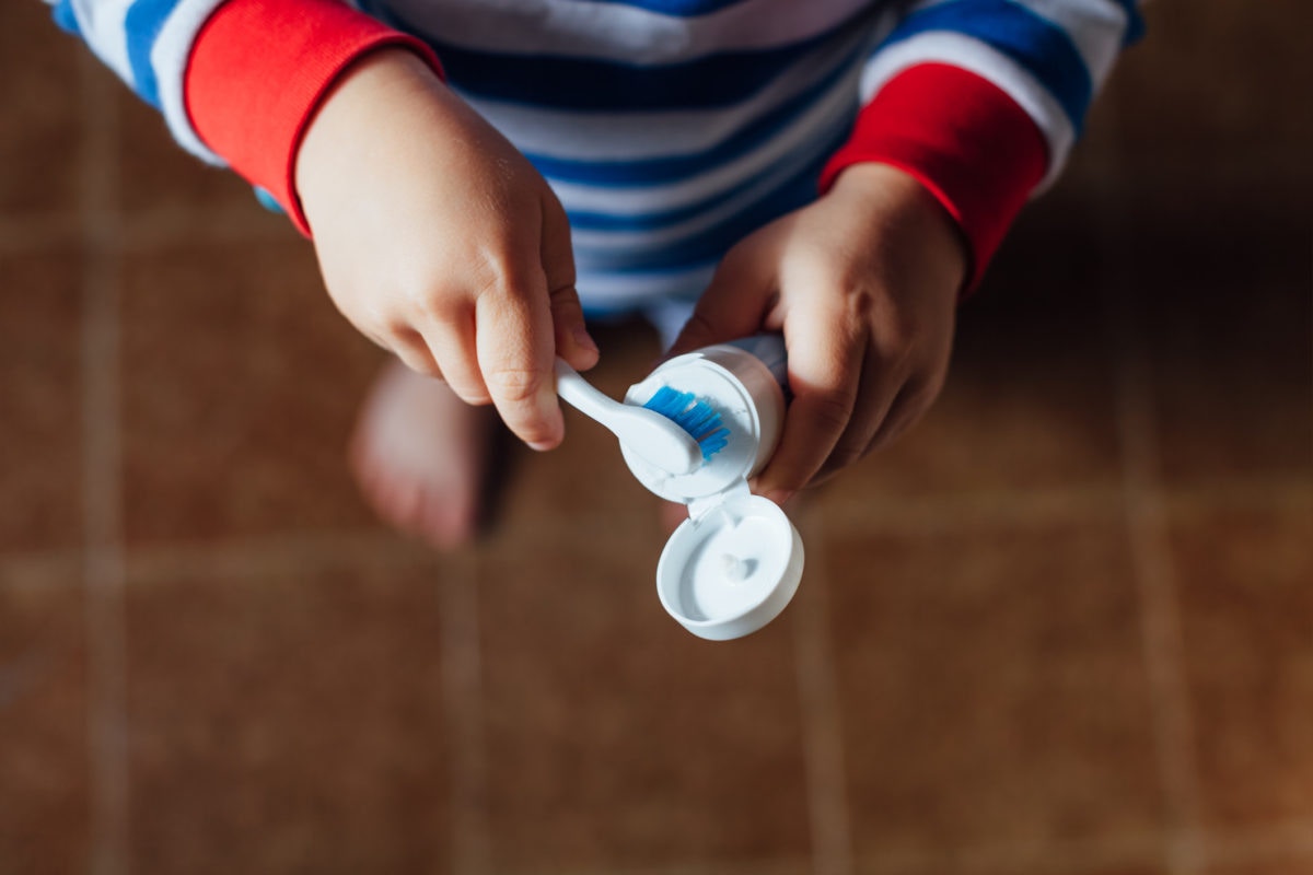 kid applyong tooth paste on brush