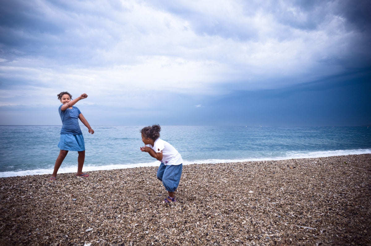 two young girls play along the sea