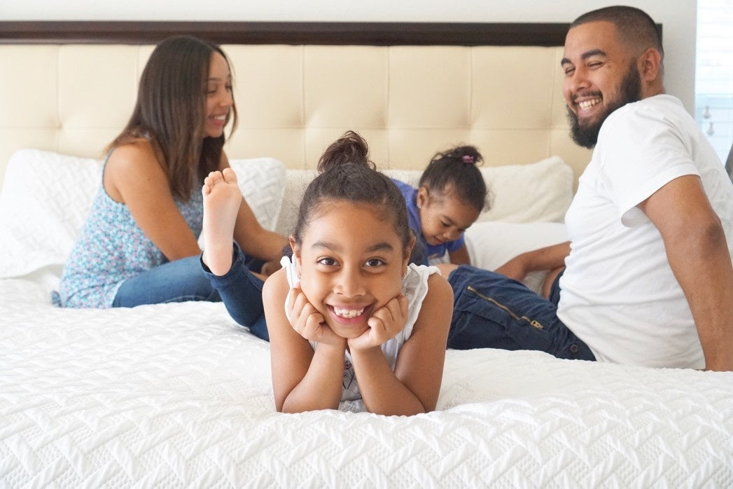 Happy parents playing with children on bed at home