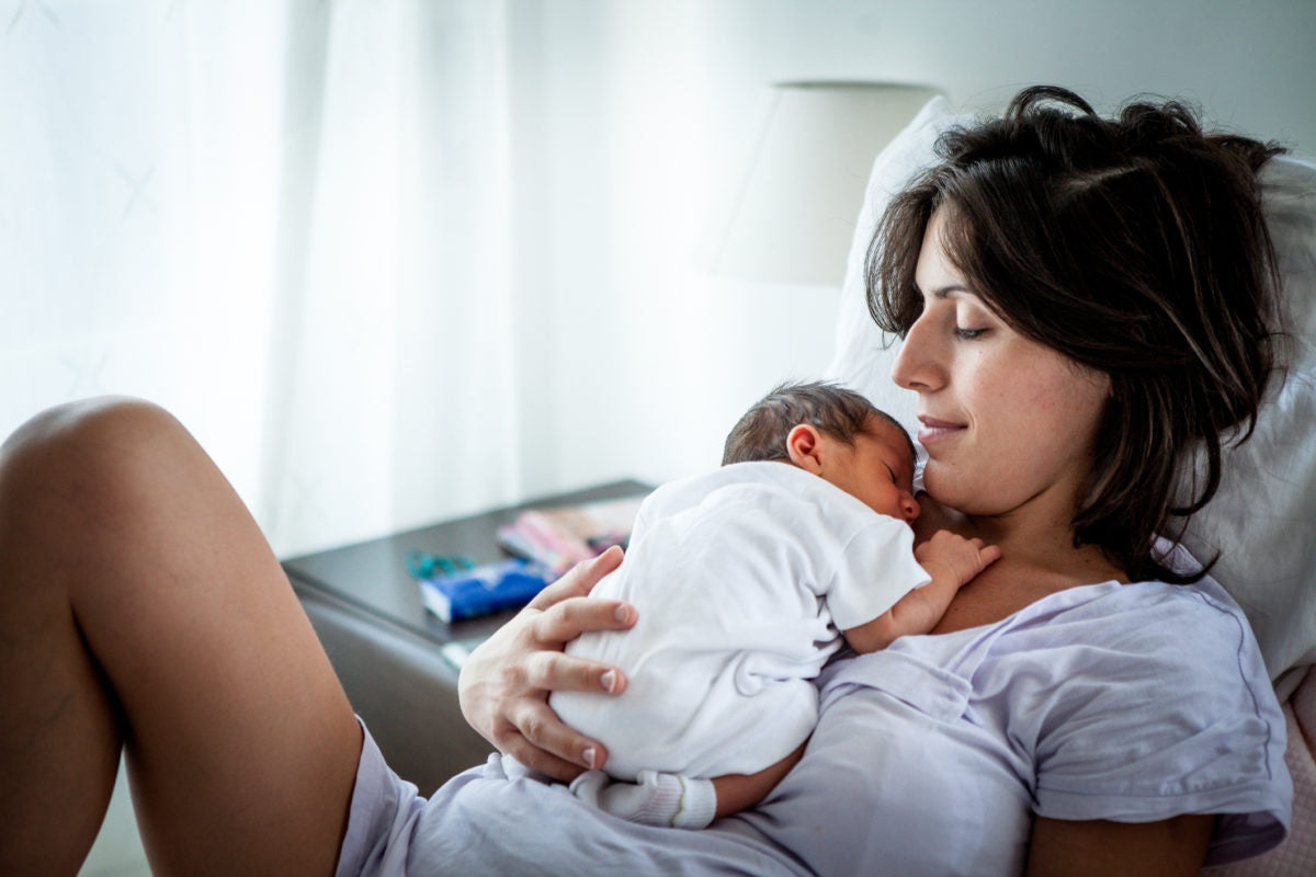 A new born baby sleeping on her mothers arms