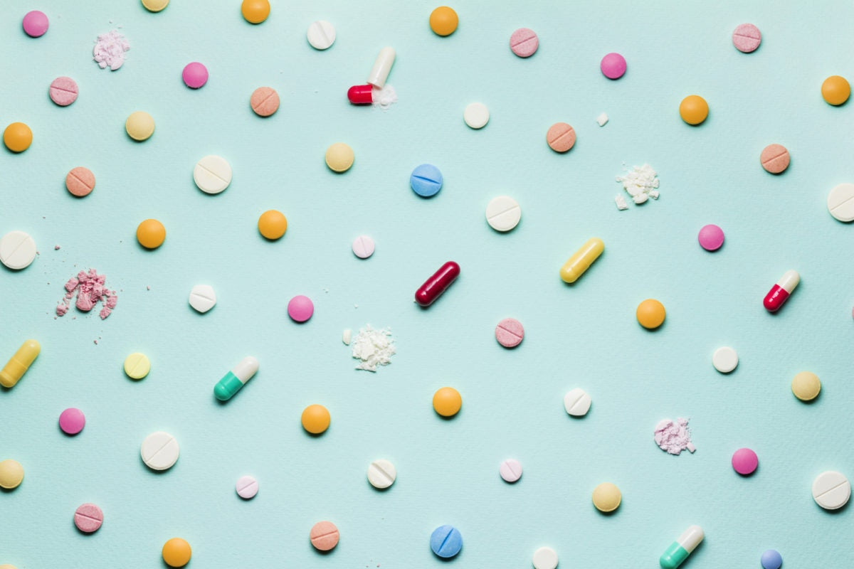 different type of pills arranged on light blue background