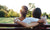 Back view of two women's hugging while sitting on a bench at the park