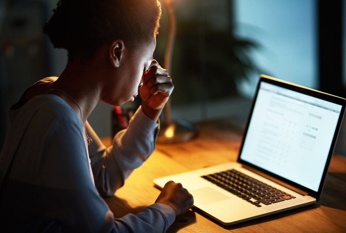 African female sitting infront of laptop and thinking with her eyes closed.