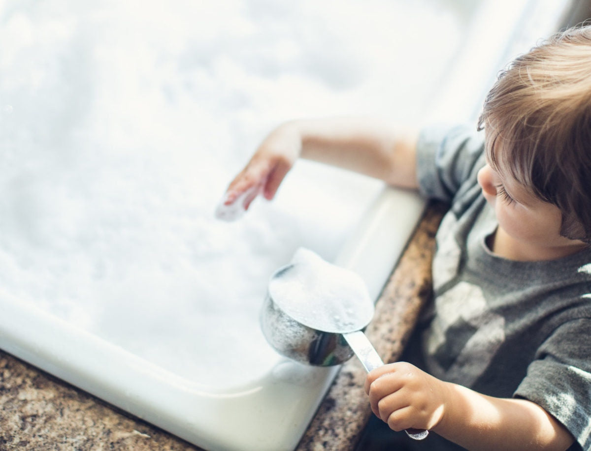 boy playing with sudds in the kitchen